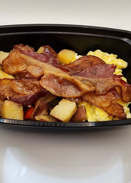 Scrambled eggs with melted cheese and crispy bacon in a black meal prep container in Denton Texas