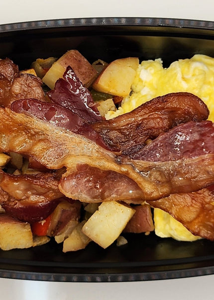 Scrambled eggs with melted cheese and crispy bacon in a black meal prep container in Denton Texas