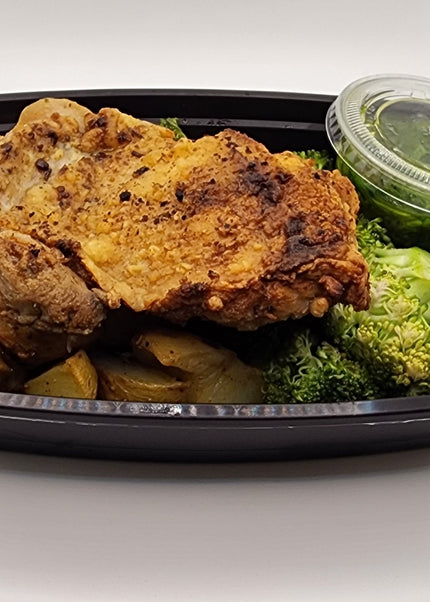 Chicken thigh topped with chimichurri sauce in a meal prep tray