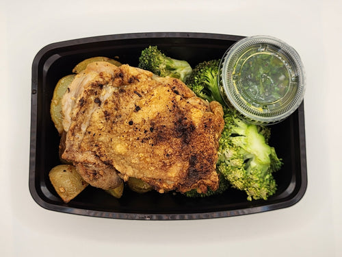 Chicken thigh topped with chimichurri sauce in a meal prep tray