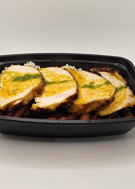 Sliced roasted chicken breast with rice and vegetables in a meal prep container