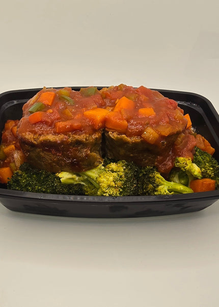 Slices of glazed meatloaf with sides in a meal prep container