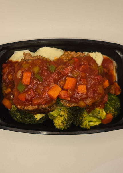 Slices of glazed meatloaf with sides in a meal prep container